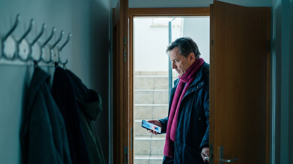 Ein Mann liest vor dem Aufbruch eine Vorsorge-Erinnerung auf seinem Smartphone